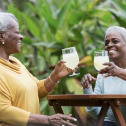 two friends with drinks in hand outdoors